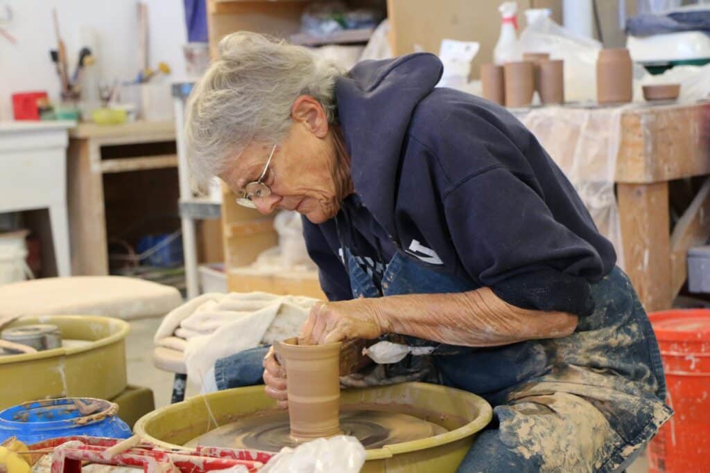 A potter works on a creating a ceramic item on a pottery wheel