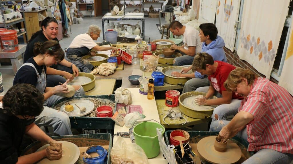 A group of students work on pottery wheels at the Clay Center