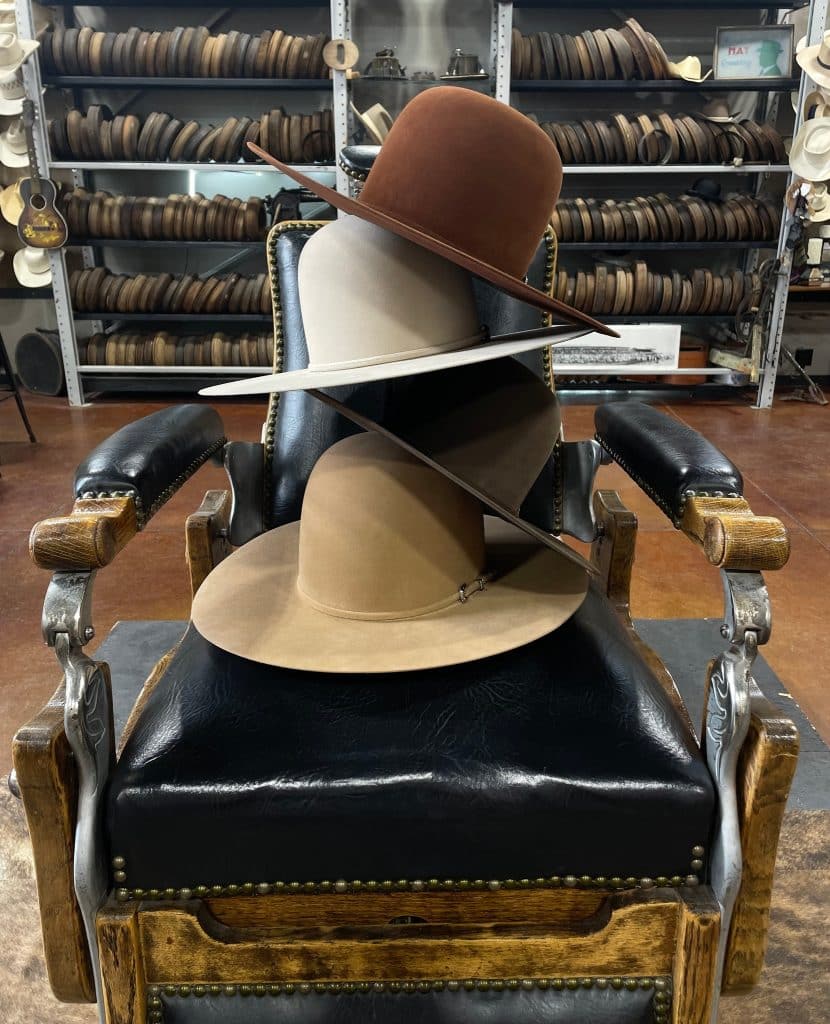 A stack of Greeley Hat Works hats in a black leather chair