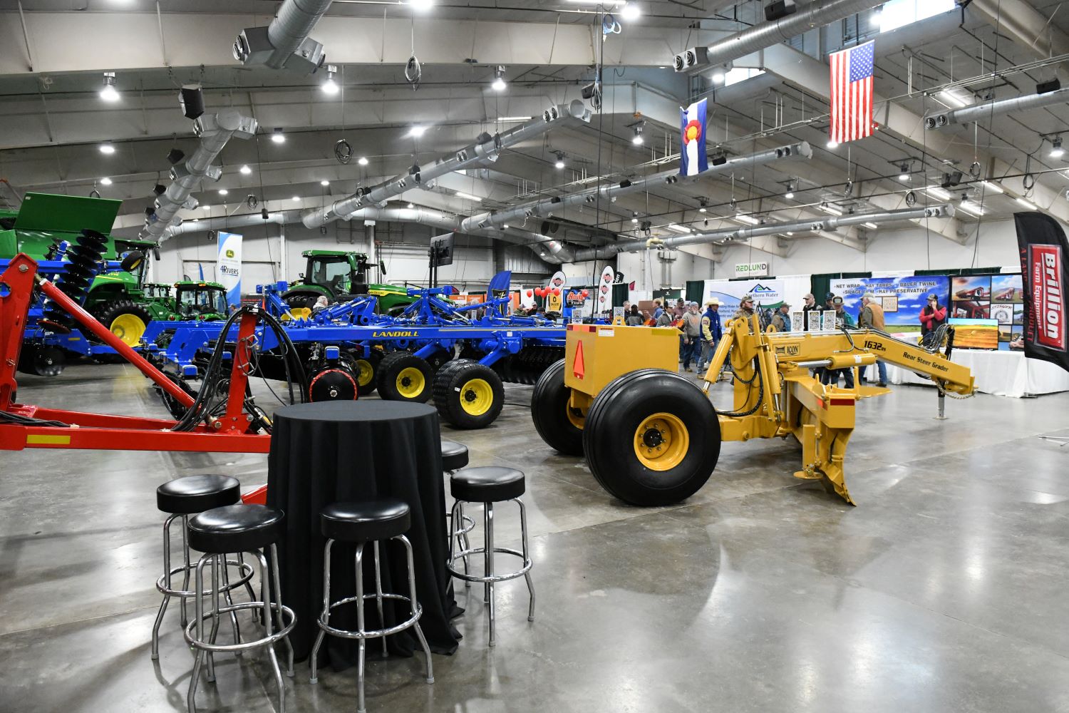 A brightly lit indoor arena full of rows and rows of large-scale farm equipment