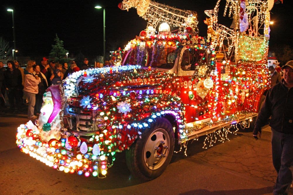 An antique firetruck covered completely in small, colorful Christmas lights
