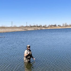 Greeley Natural Area Technician II Kaitlyn Ikenouye wades into the waist high water at the Poudre Ponds to check its temperature.