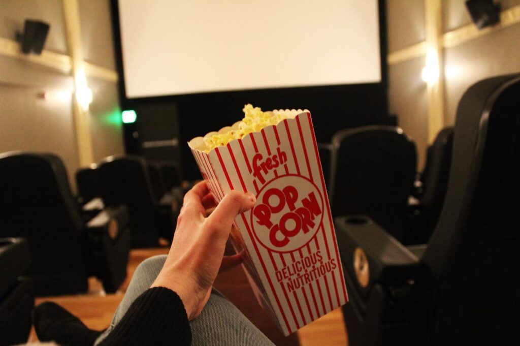Photo of a container of popcorn being held by a customer at the movies.
